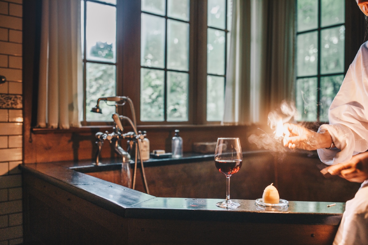 person lighting candle near bathtub