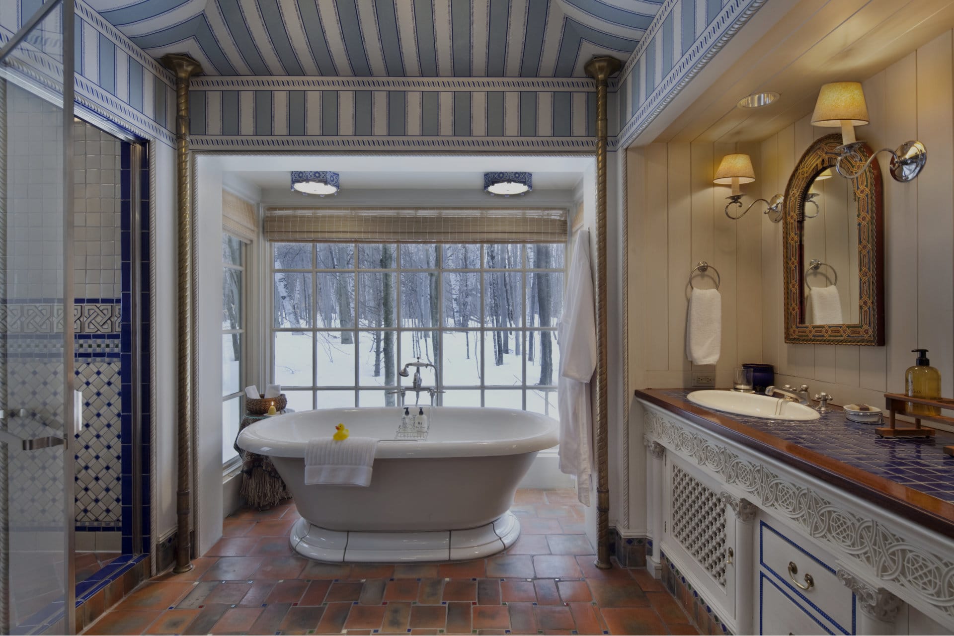 a white bath tub placed in front of a window looking out at snowy woods