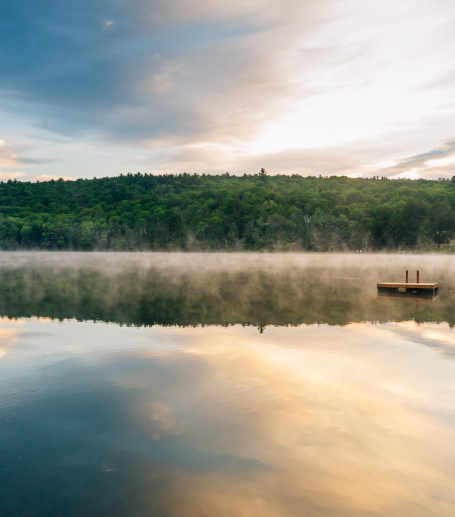 Lake at dusk with woods in the background