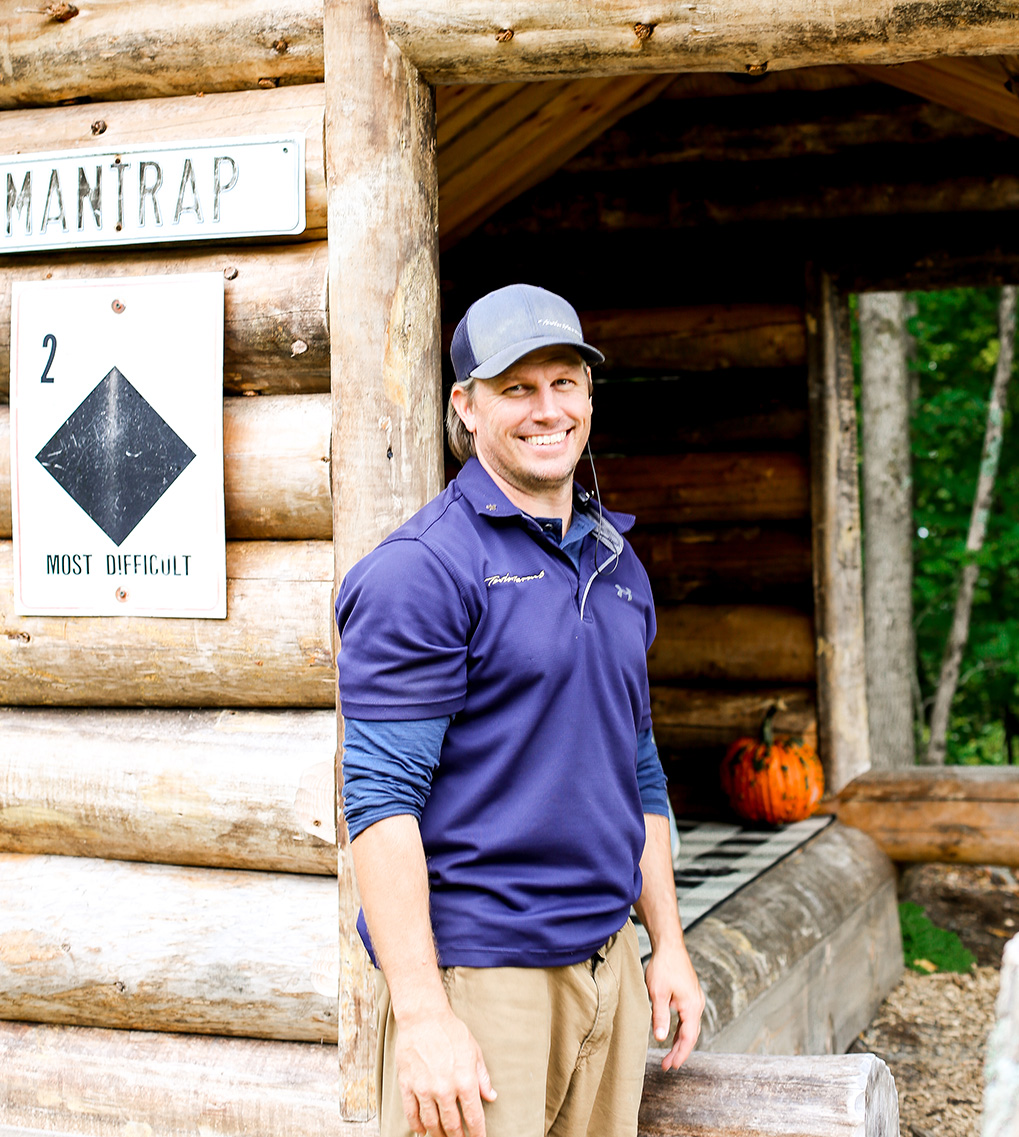 employee standing in front of a wood cabin